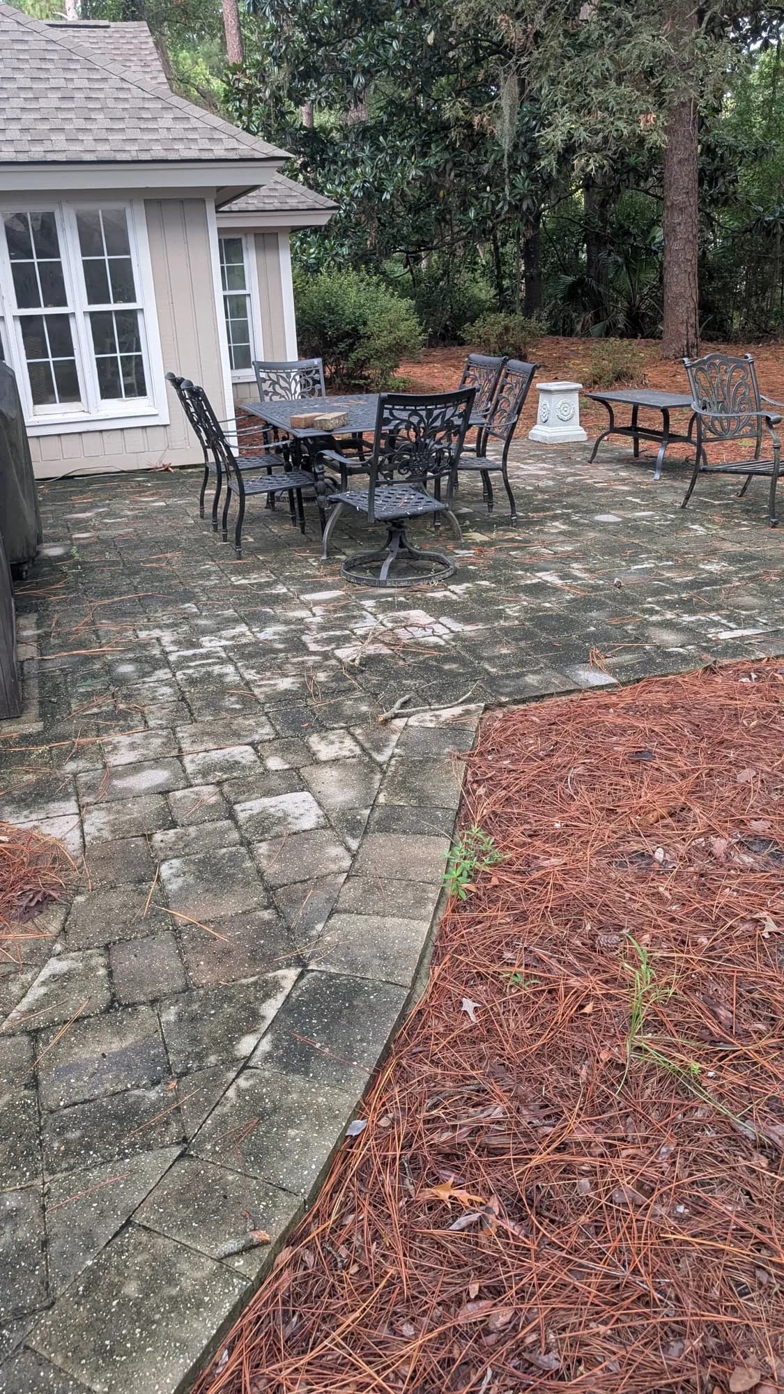 Paver patio with outdoor furniture mottled dark and dirty before cleaning