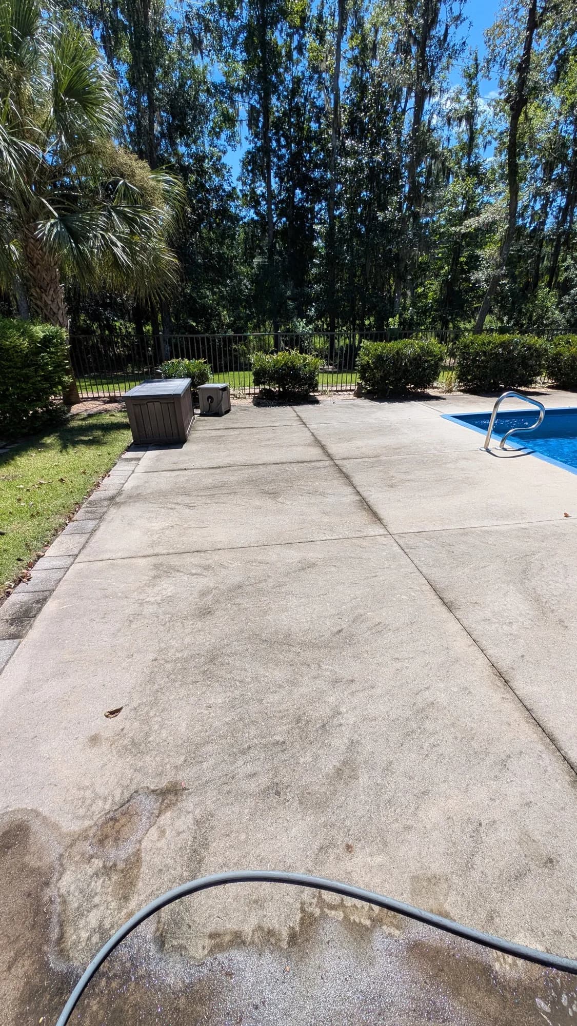 Poolside concrete deck with dark staining before cleaning