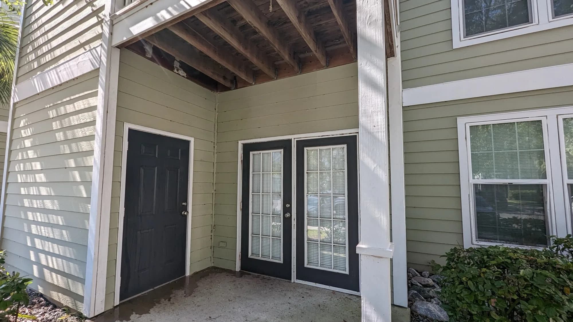 Covered screened patio with stained concrete floor before cleaning